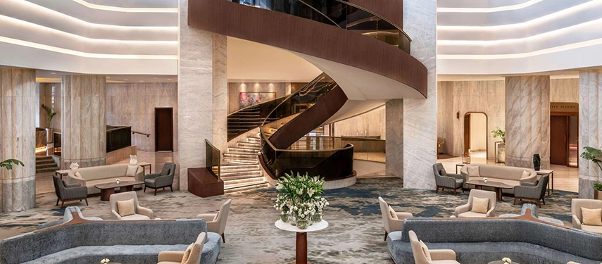 A grand marble lobby with curved seating and a sweeping central staircase creates an elegant first impression at the Sofitel Cairo Nile Hotel.