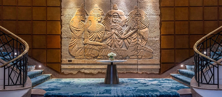 A carved stone relief of ancient Egyptian figures forms a dramatic focal point between twin staircases in the Sofitel Cairo Nile Hotel lobby.