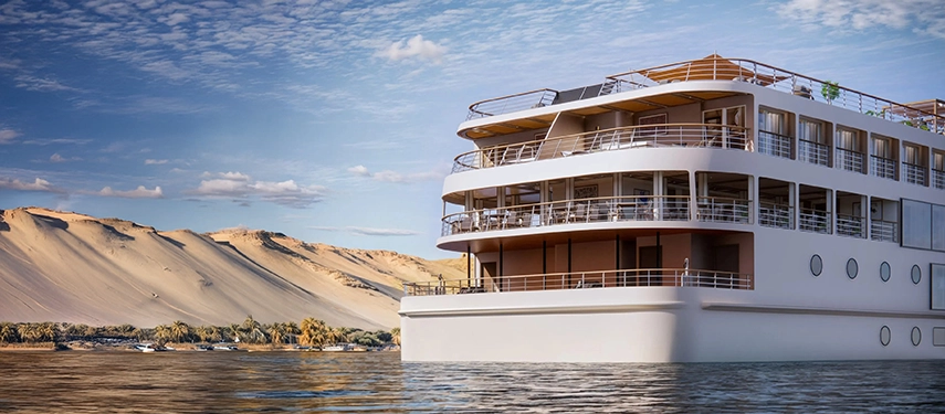 The stern view of A&K Sanctuary Nile Seray revealing tiered decks and wraparound balconies as the vessel cruises through Egypt’s desert landscapes.