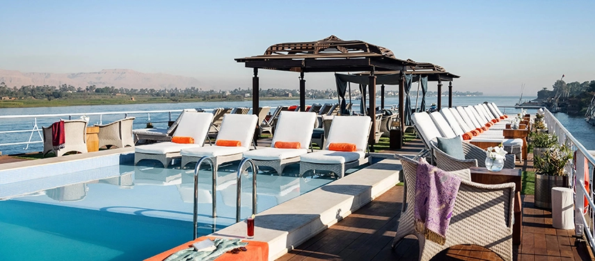 The open sun deck aboard A&K Sanctuary Nile Seray featuring a swimming pool, shaded loungers and uninterrupted river views.