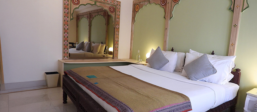 Elegant bedroom at The Stepwell House showcasing Marwari arch designs and a large mirror.