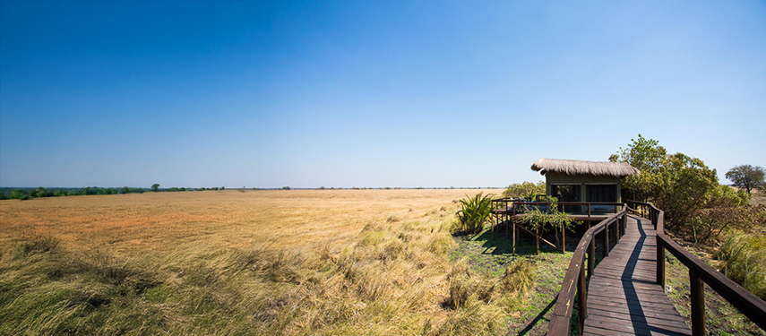 Raised boardwalk leading to a private safari tent overlooking the vast grassy plains
